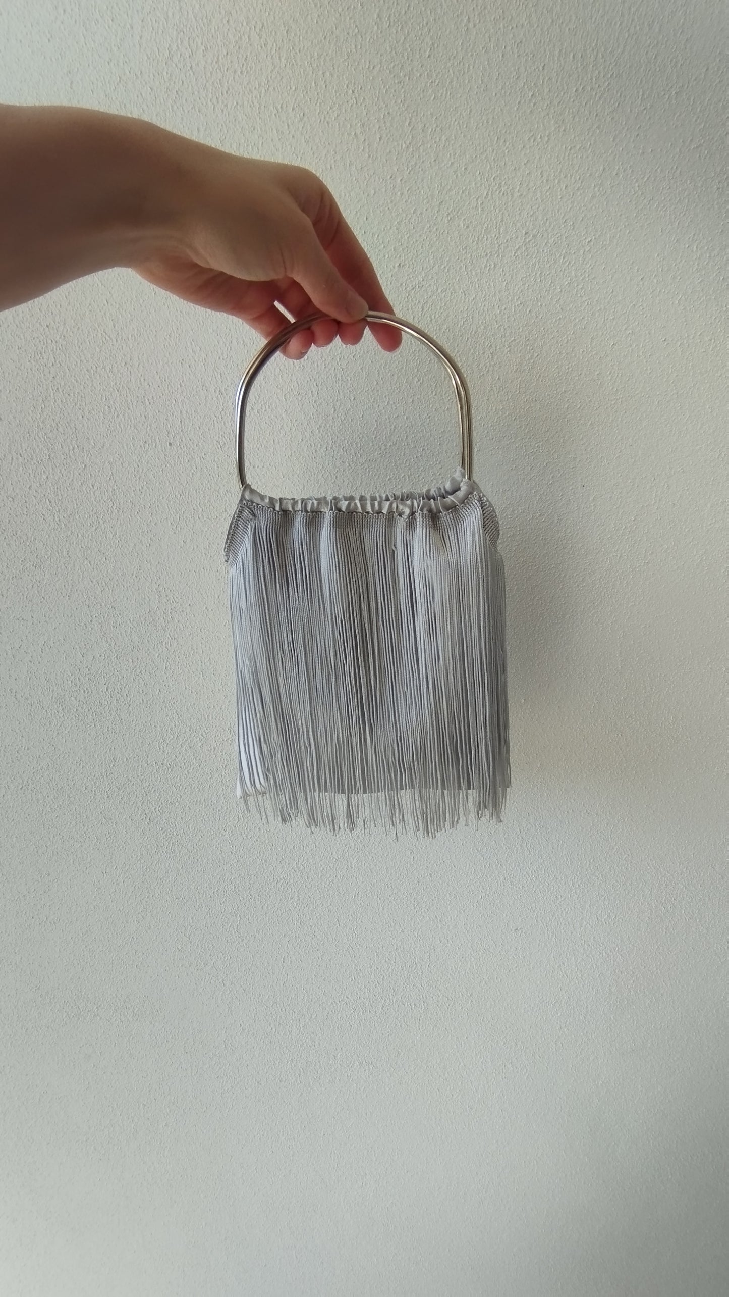 Borsa a sacchetto con frangia di nappe e manico in metallo