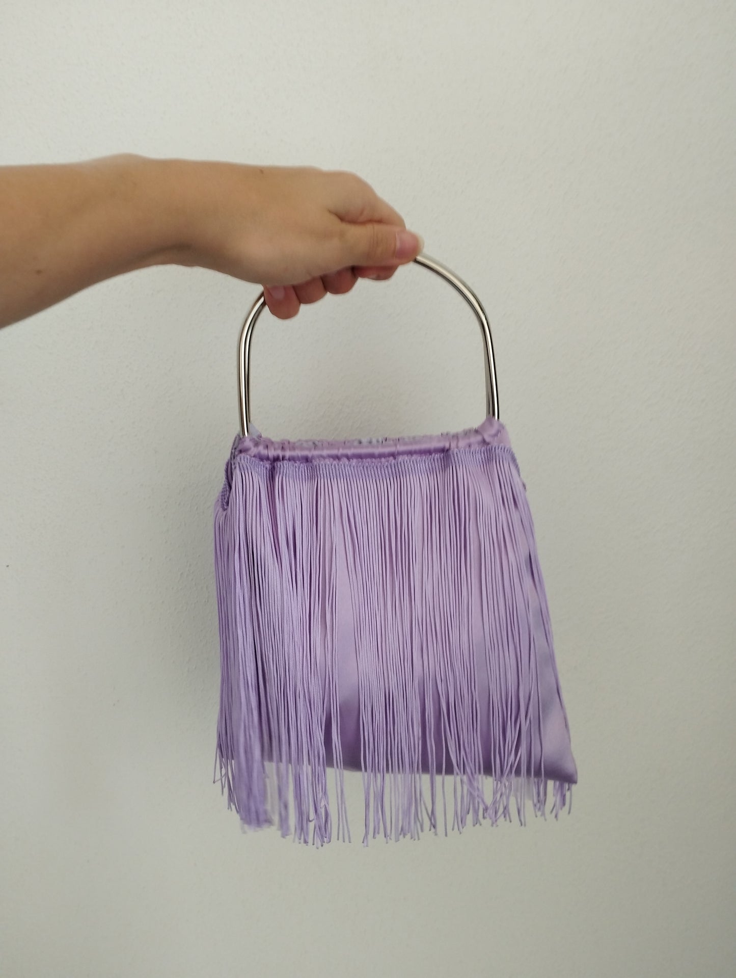 Borsa a sacchetto con frangia di nappe e manico in metallo