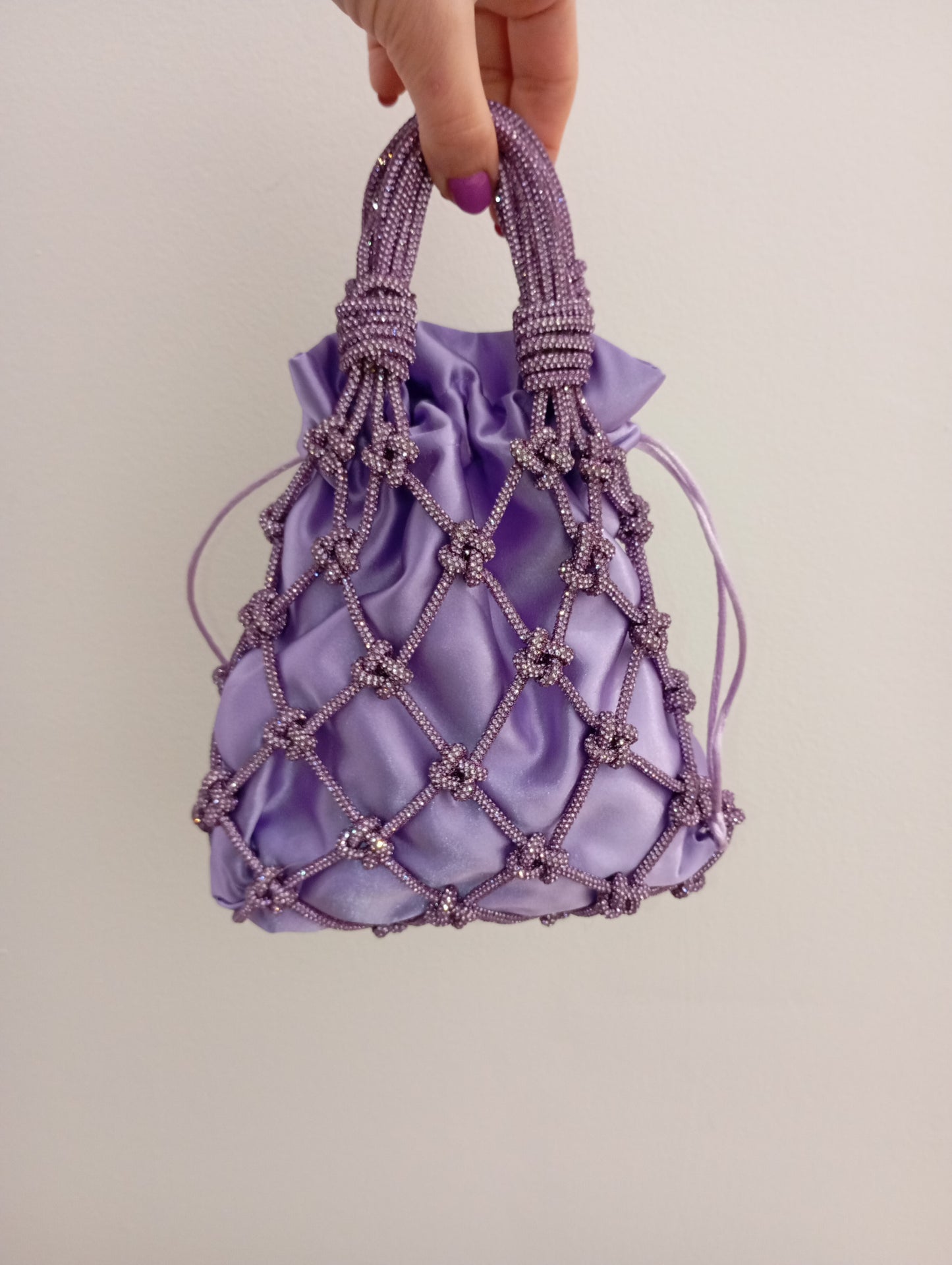 Borsa a rete realizzata con un luminoso filato strass color lilla intrecciato a mano. Sacchetto interno in raso satin intercambiabile.