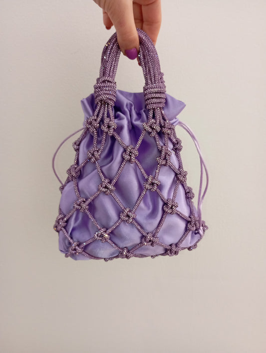 Borsa a rete realizzata con un luminoso filato strass color lilla intrecciato a mano. Sacchetto interno in raso satin intercambiabile.